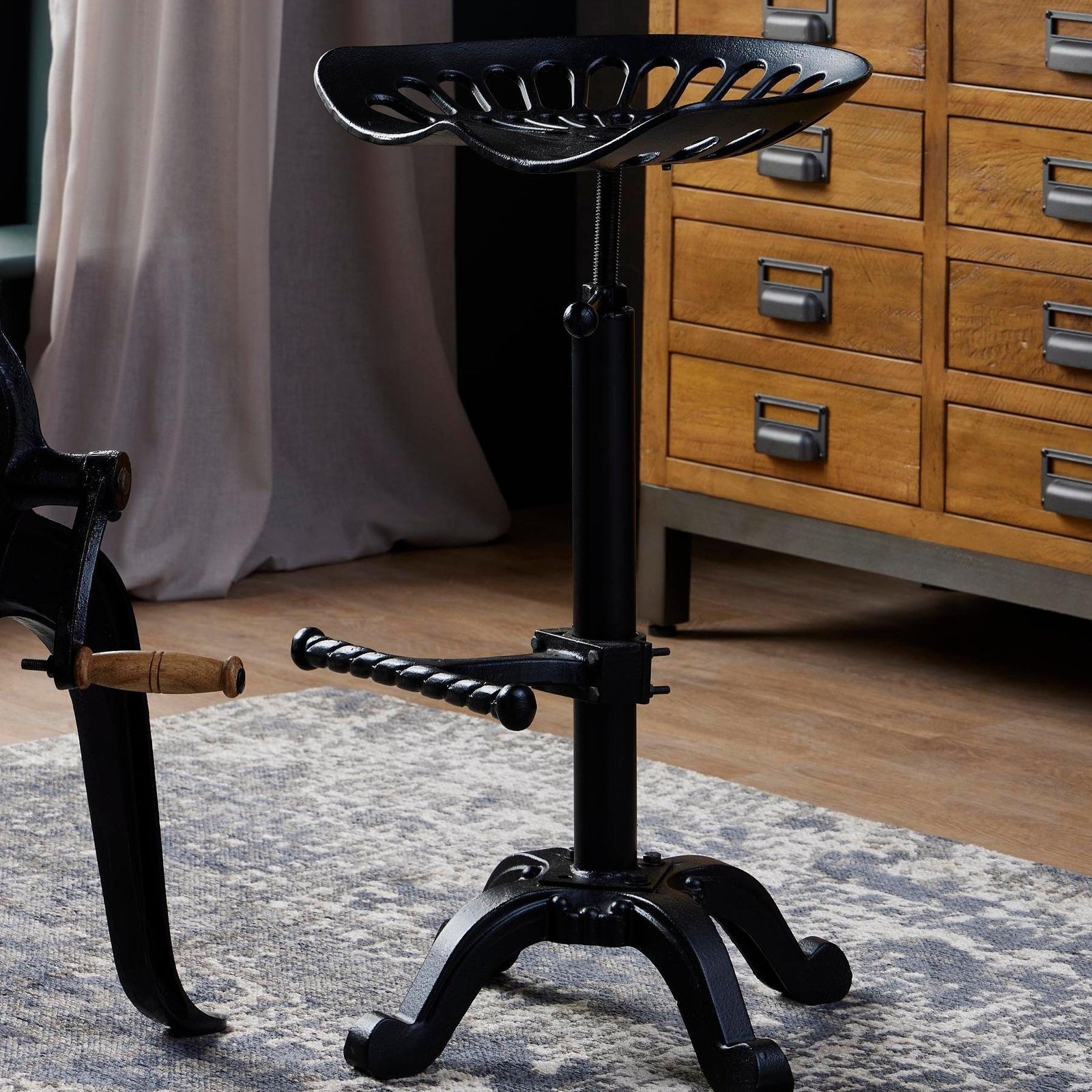 Black metal Dine and Dwell Norwich adjustable tractor bar stool with a modern design and ergonomic seat.