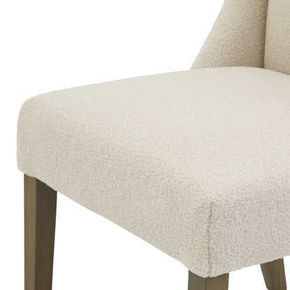 Cream upholstered Dine and Dwell Bristol Boucle dining chair with wooden legs, showcasing plush fabric and modern design.