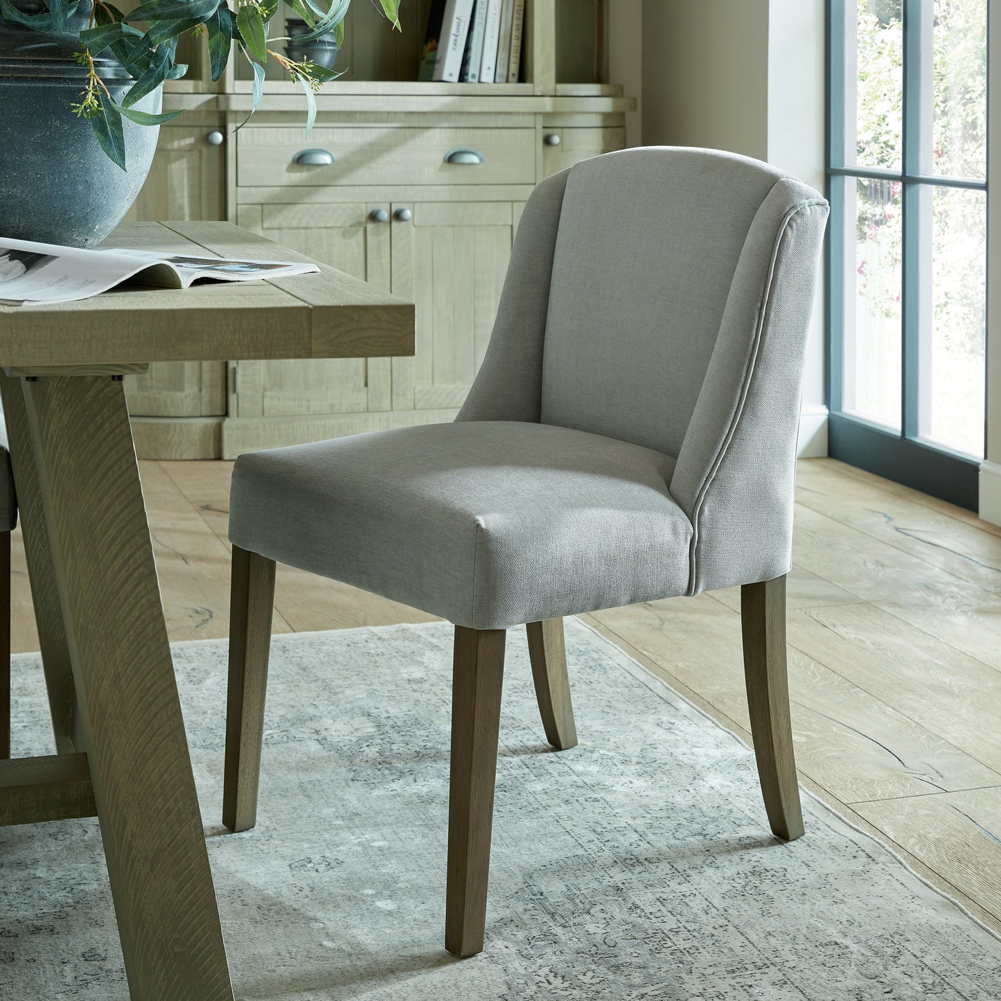 Grey upholstered Dine and Dwell Bristol dining chair with wooden legs, showcasing a modern and comfortable design.