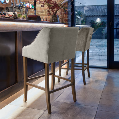 Grey upholstered Dine and Dwell Liverpool bar stool with fabric seat and wooden legs, modern design for kitchen or bar area.