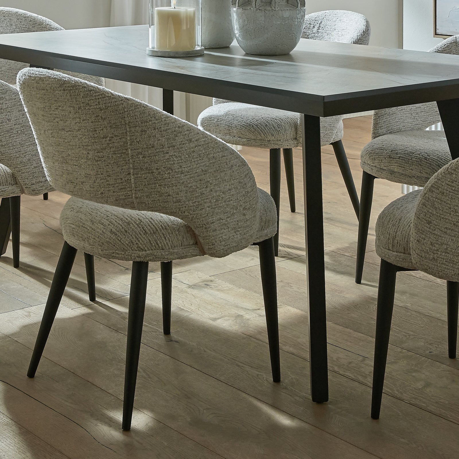 White upholstered Dine and Dwell Sandwell curved dining chair with black metal legs, modern and stylish for dining rooms.